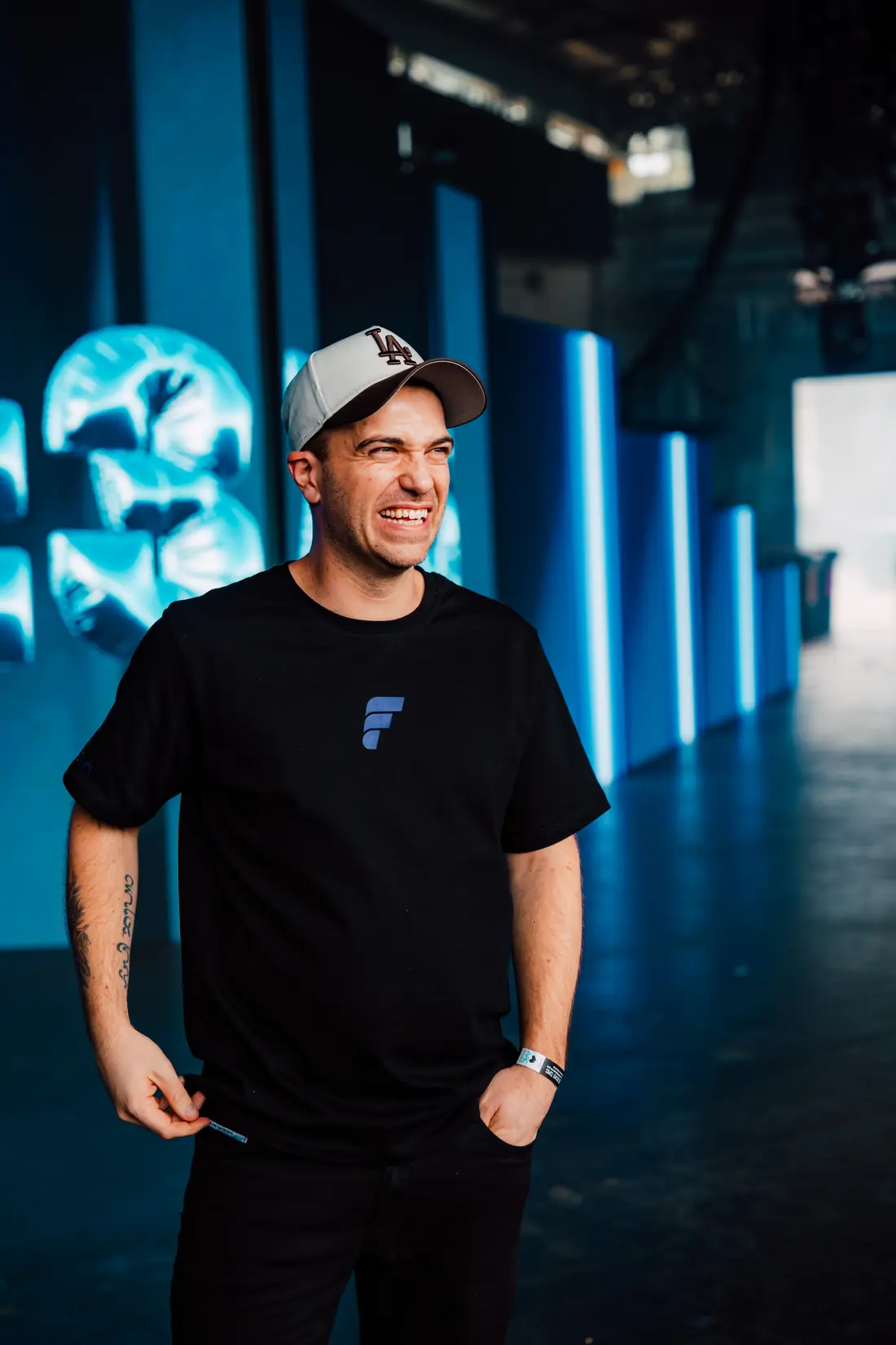 Mark Middo laughing backstage, lit blue by the stage screens